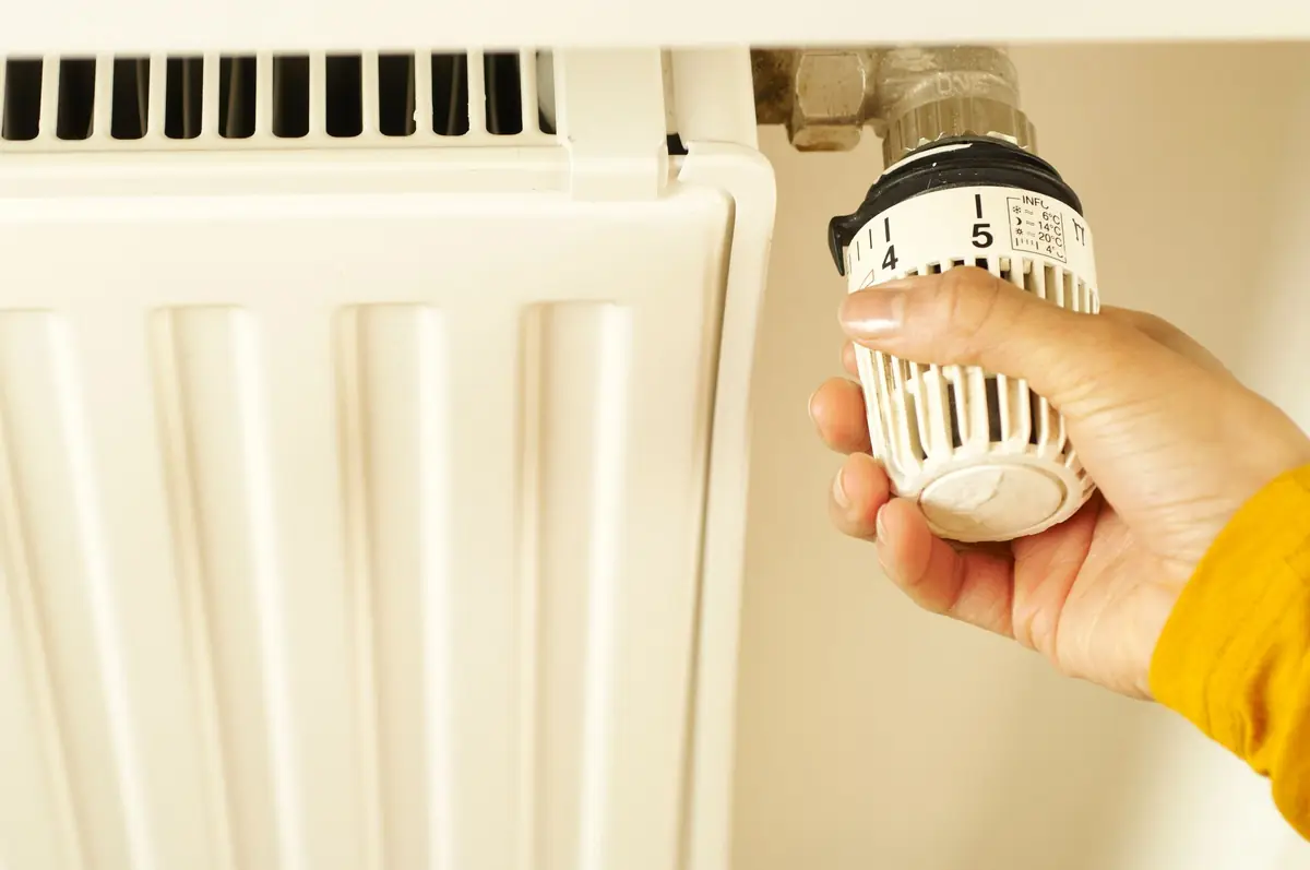 A hand turning a radiator valve.