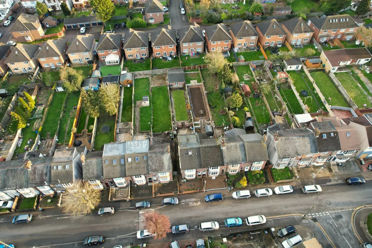 Rows of houses with long back gardens in an English suburb, seen from above.