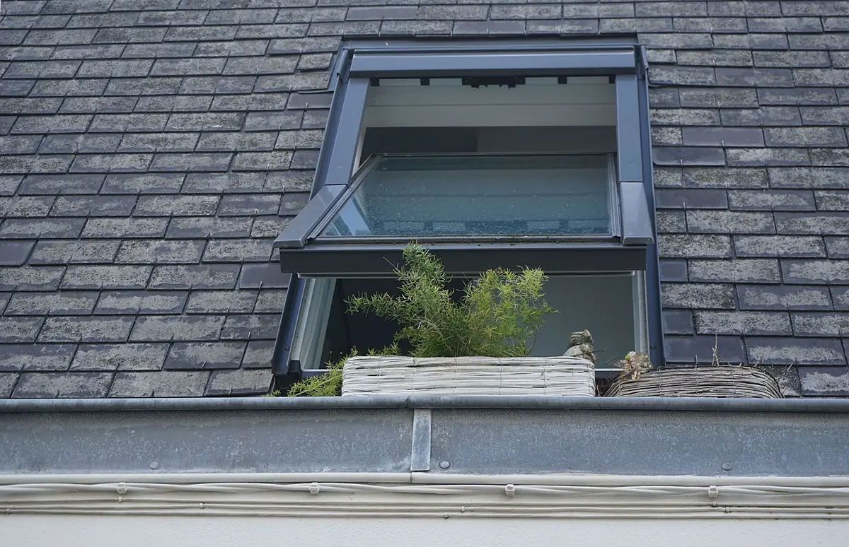 An open roof window in a slate roof.