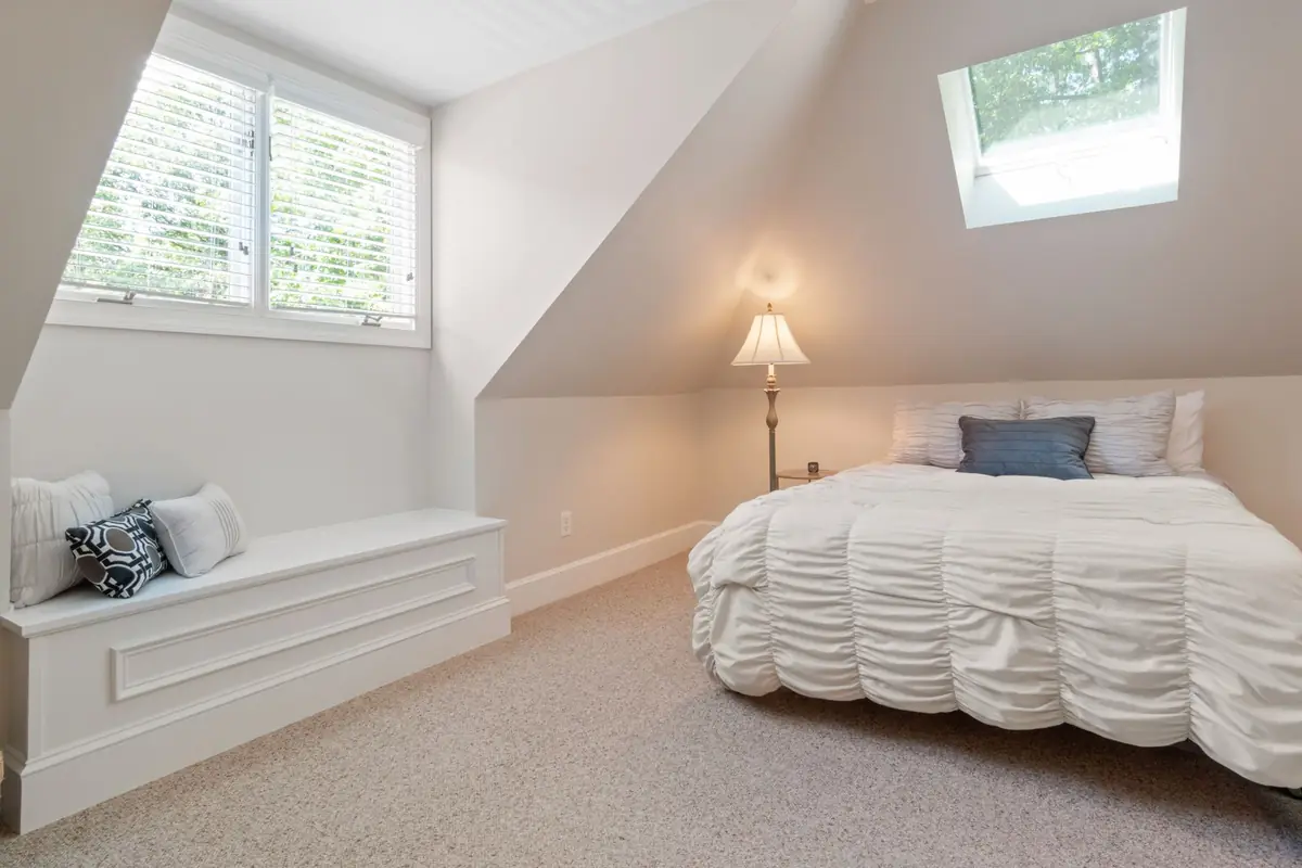 A bedroom under a sloping ceiling with a roof window.