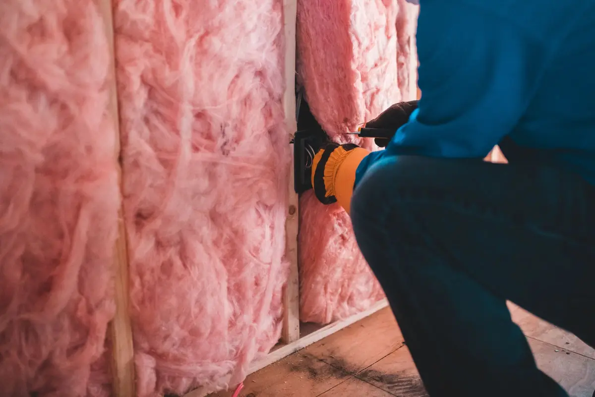A builder fitting insulation into a ceiling.