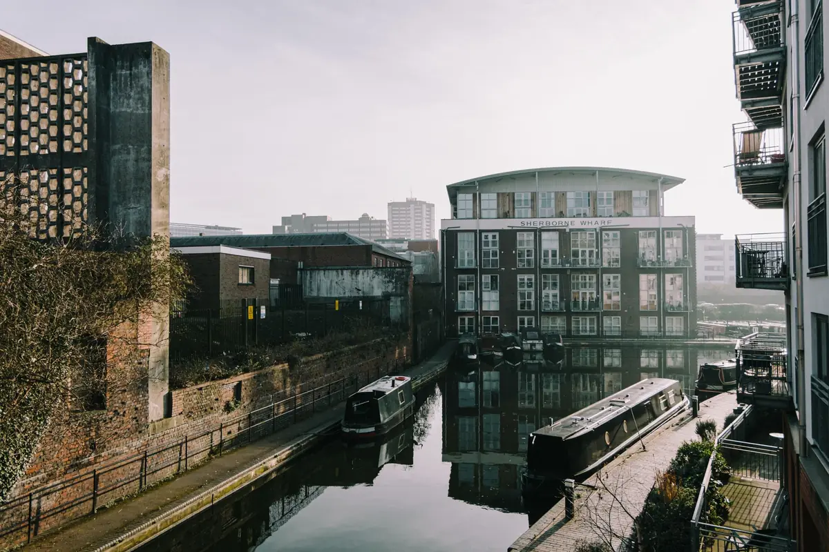 A canal through Birmingham city centre, with narrowboats moored by the towpath.