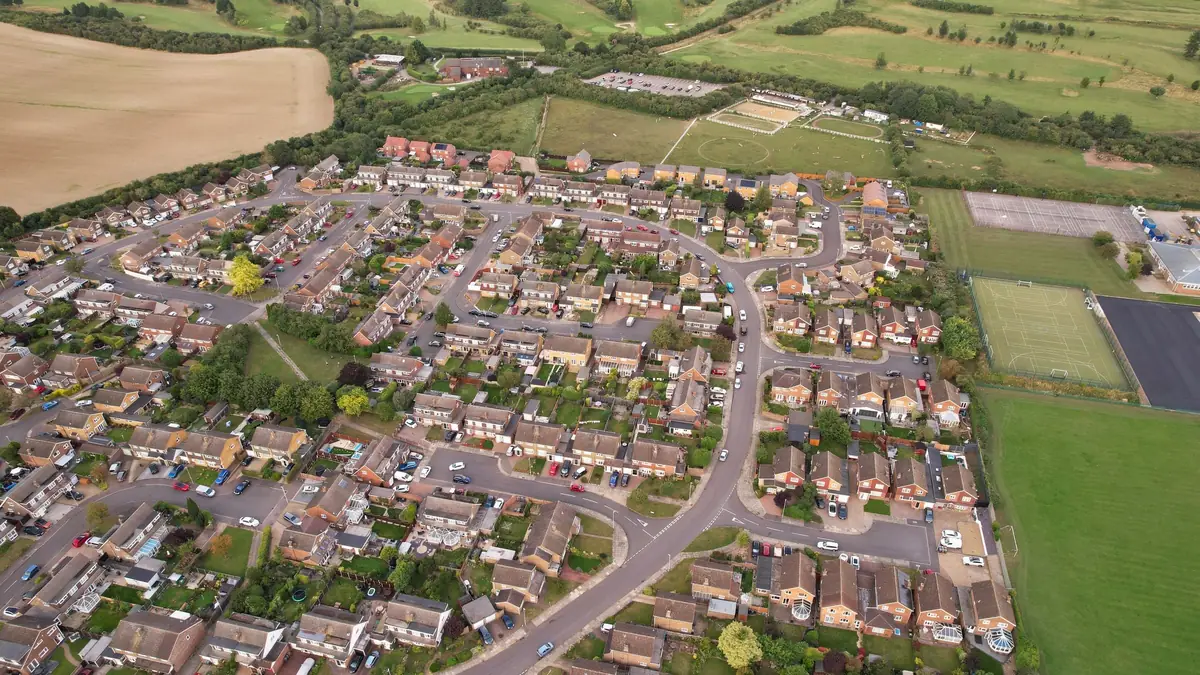 An aerial view of a modern housing estate beside open fields.