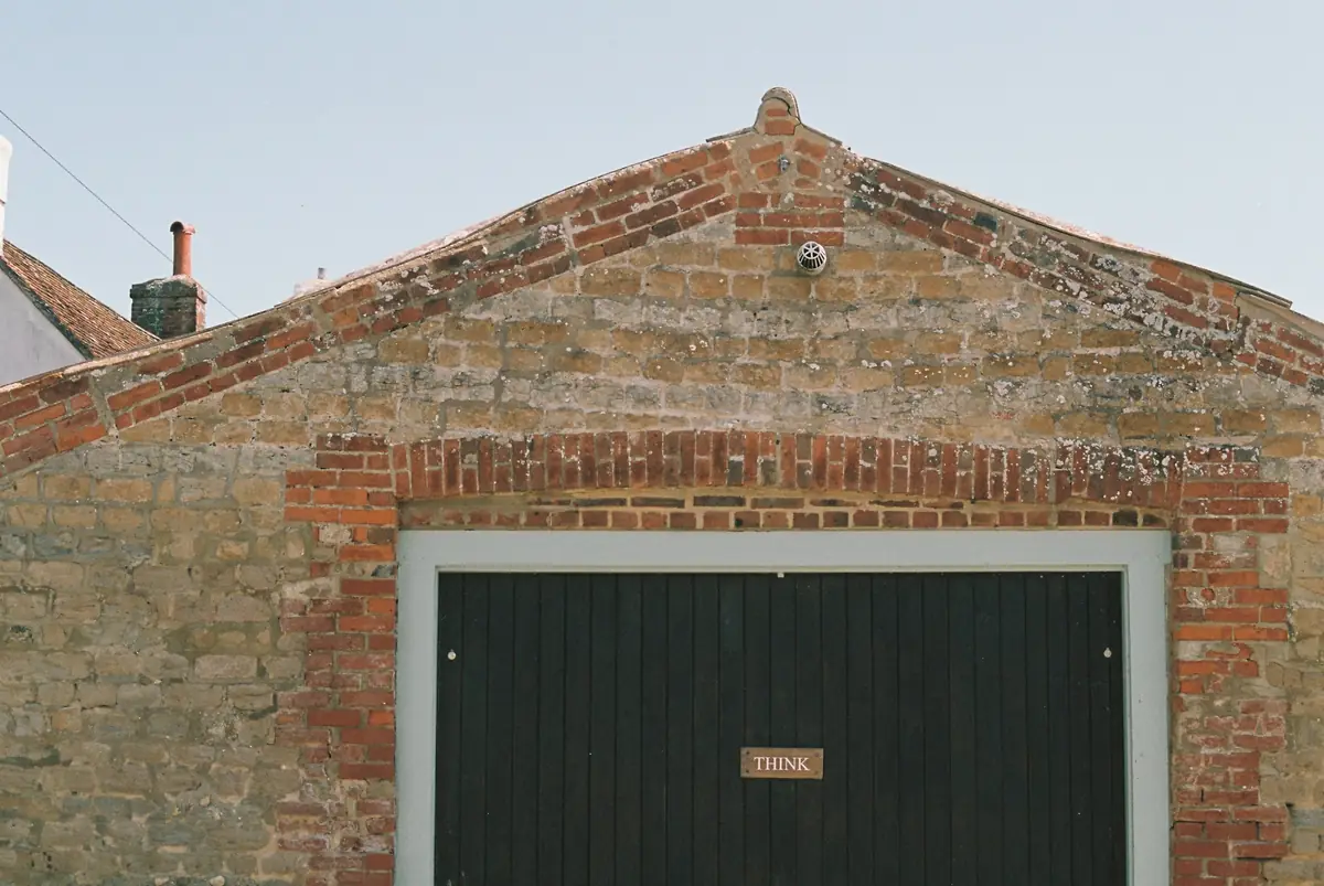 A brick garage with a dark green up-and-over door.